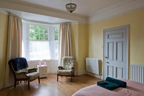a bedroom with a bed and two chairs and a window at Cenotaph View, Bardon Mill in Hexham