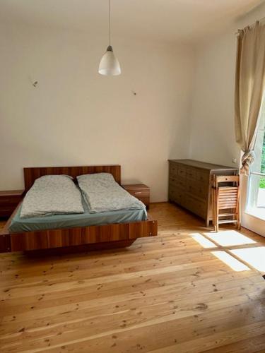 a bedroom with a bed and a wooden floor at Giulia Vendégház in Balatonboglár