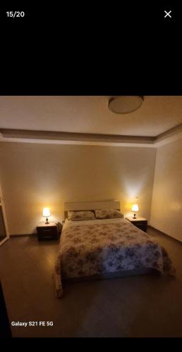 a bedroom with a large bed with two lamps on it at jardin de raisin in Bouznika