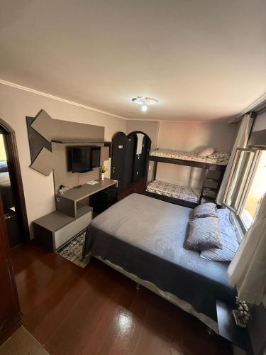 a bedroom with two bunk beds and a desk at HOSTEL FAMILIA ZANATTA in Caxias do Sul