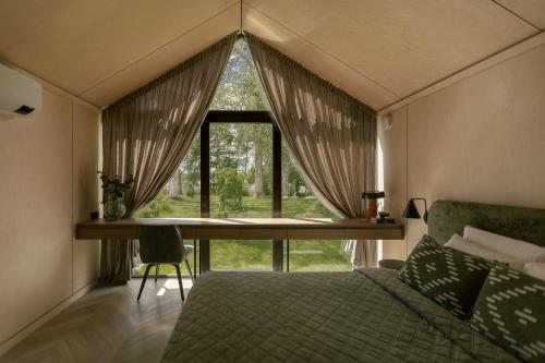 a bedroom with a bed and a desk and a window at Lėtai resort, Lakefront Nature Stay with Sauna in Eželiškės