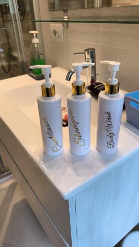 three white soap bottles sitting on top of a counter at Maddalena House in Varenna