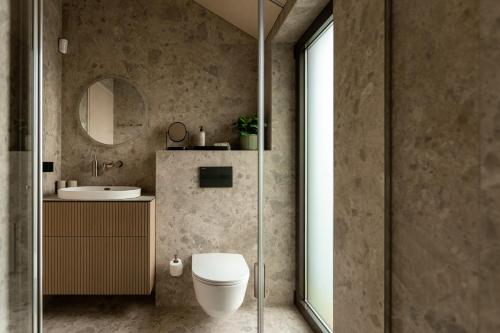 a bathroom with a toilet and a sink and a mirror at Lėtai resort, Lakefront Nature Stay with Sauna in Eželiškės