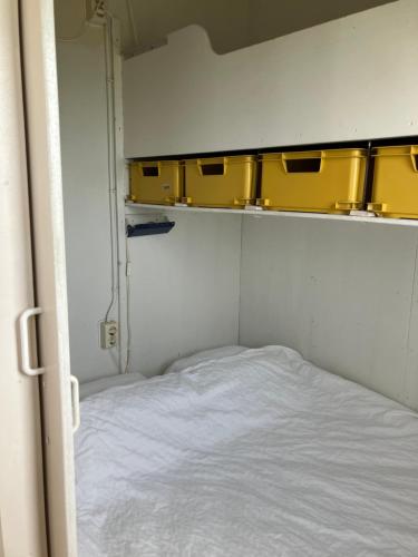 a small room with a bed and yellow cabinets at Strandelijk plekje in Nieuwerkerk