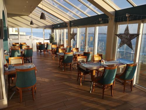 ein Restaurant mit Tischen und Stühlen in einem Raum mit Fenstern in der Unterkunft WatersEdge Hotel in Cobh
