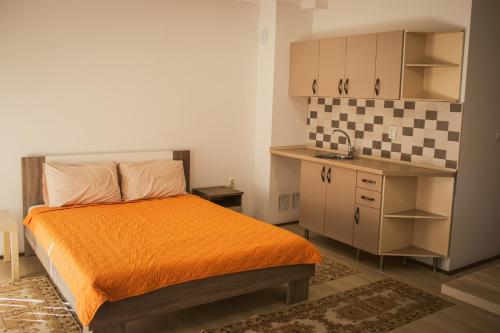 a small bedroom with an orange bed and a kitchen at Stara Charshija - Old Bazaar in Bitola