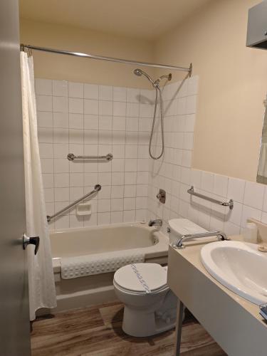 a bathroom with a tub and a toilet and a sink at Auberge Cap Martin in La Pocatiere