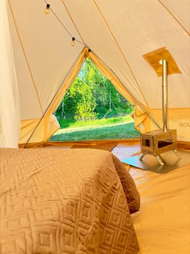 a tent with a bed in a room with a window at Glamping Arctic Ukuli in Rovaniemi