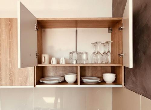 a cupboard with plates and glasses and dishes in it at Alice's Home in Surčin