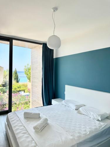a bedroom with a white bed with a large window at Sea't La Vie Villas in Hamallë
