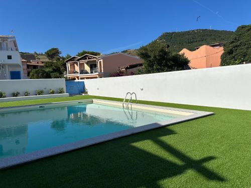 a swimming pool in a yard next to a white fence at AZZURRO meraviglioso attico a pochi passi dal mare in Valledoria