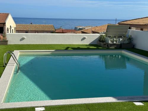 a large blue swimming pool with the ocean in the background at AZZURRO meraviglioso attico a pochi passi dal mare in Valledoria