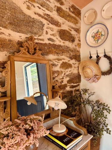 a mirror and a table with a book and flowers at Casa da Rigueira in Moreira do Lima