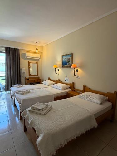 a hotel room with three beds and a mirror at Paradise Hotel in Kos