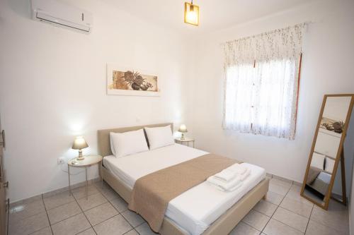a bedroom with a white bed and a mirror at Anemoessa in Ammoudia
