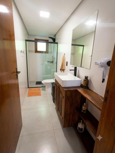 a bathroom with a sink and a toilet and a mirror at Casa das Bananeiras - 1 Quarto * Rota do Vinho in Bento Gonçalves