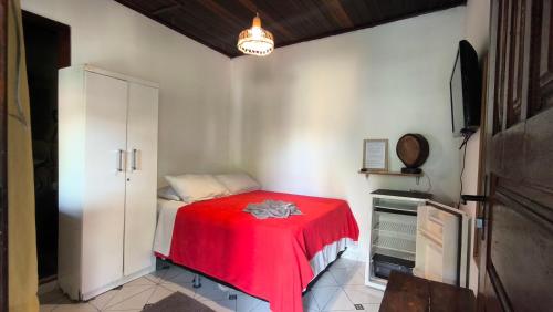 a bedroom with a red blanket on a bed at Hospedagem La Bilbaina in Porto Seguro