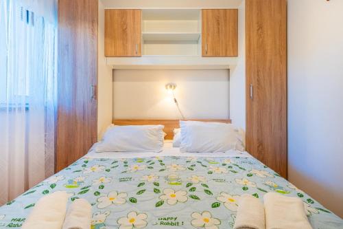 a bedroom with a bed with a floral bedspread at Apartmani Vitković II Cres in Cres