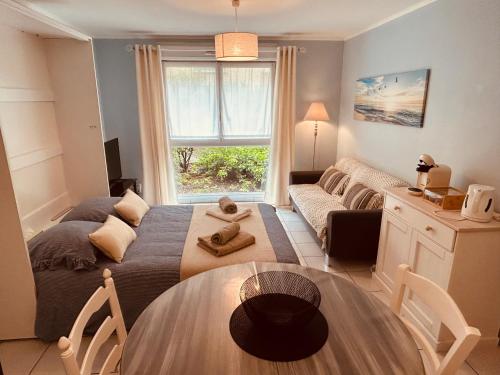 a living room with a bed and a table at Charmant studio proche gare - parking privatif individuel clos in Arras