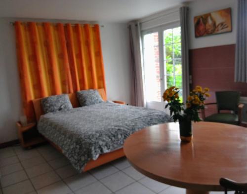 a bedroom with a bed and a wooden table and a tableablish at Logement entier jardin clos parc chien A1 A29 5 mn in Herleville