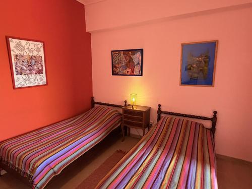 two beds in a room with red walls and a table at Art & Motion Union - Guest Room 2 in Apoíkia