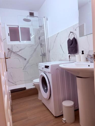 a bathroom with a washing machine next to a sink at Casa Lana - Cozy Beachside Studio in Puertito de Güímar