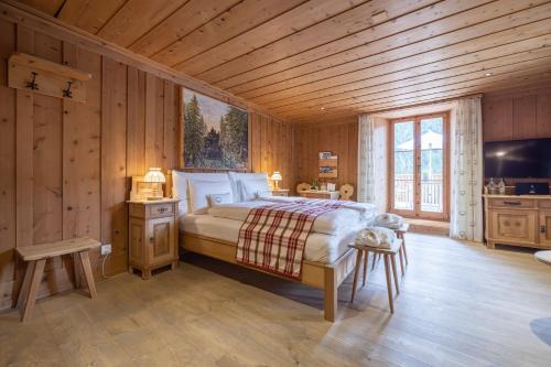a bedroom with a bed in a wooden room at Relais & Châteaux IN LAIN Hotel Cadonau in Brail