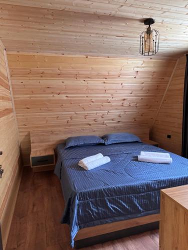 a bedroom with a bed with a wooden wall at Chachkari Cottage in Gogasheni