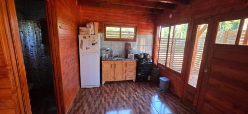 a kitchen with a white refrigerator and wooden walls at Encantos del Monte in Gobernador Roca