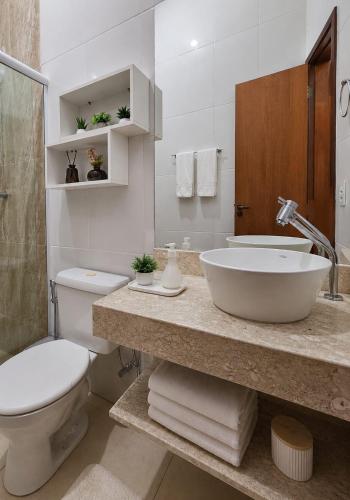 a white bathroom with a sink and a toilet at Casa Harmonia - Ar Condicionado in Bom Jesus da Lapa