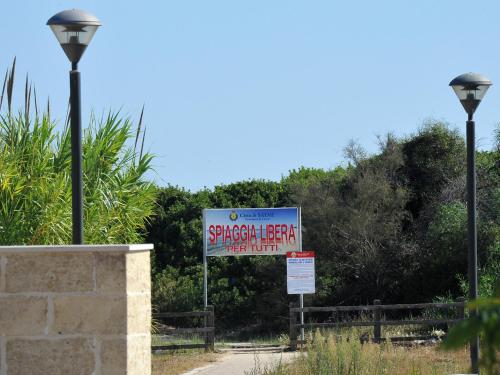 a sign for a swimming facility with two street lights at Casa vacanze spiaggia dorata in Marina di Pescoluse