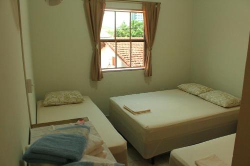 a small room with two beds and a window at Hospedaria Servos de Maria in Aparecida