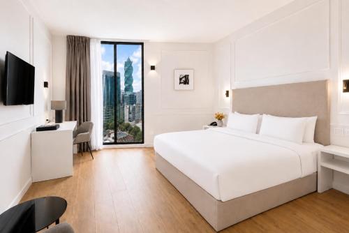 a white bedroom with a large bed and a desk at Hotel Mio Panamá in Panama City