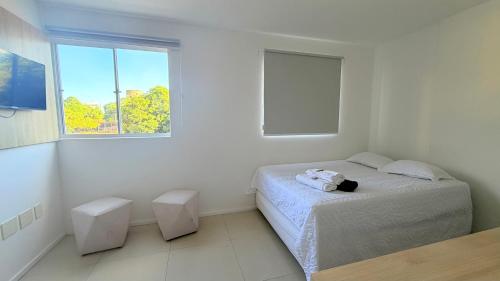 a white bedroom with a bed and a window at Studio V Ininga in Teresina