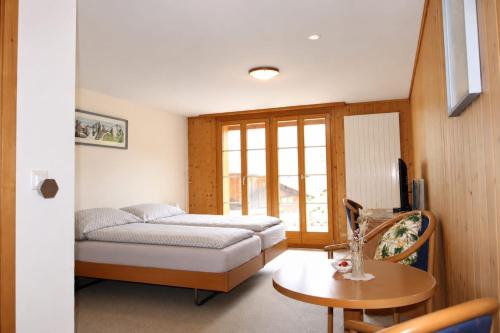 a small bedroom with a bed and a table at Hotel Restaurant Waldrand in Isenfluh