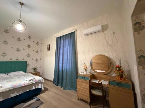 a bedroom with a bed and a desk with a mirror at Dadu's Guesthouse in Samtredia