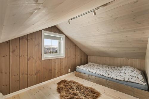 a small bedroom with a bed in a room with a window at Cozy and modern cabin in Vossevangen