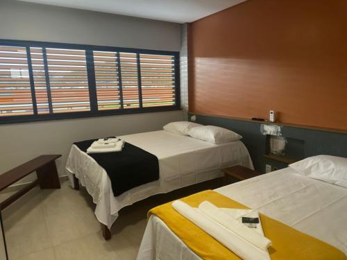 a room with two beds and a table and chairs at Prime Pousada - Posto Sudoeste Queimadas in Queimadas