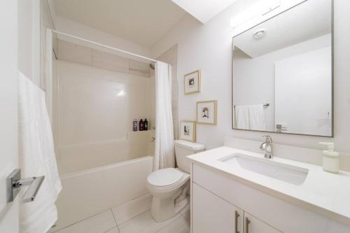 a white bathroom with a sink and a toilet at Chic Hideaway - King Bed - Fireplace - Garage - AC - DT and WEM in Edmonton