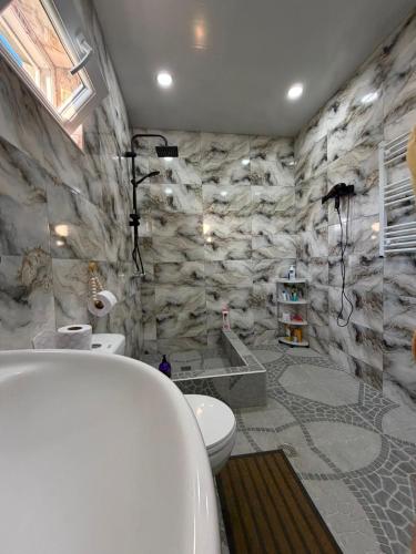a bathroom with a tub and a stone wall at Dadu's Guesthouse in Samtredia
