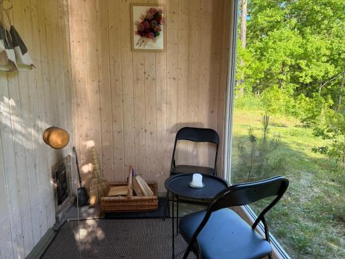 a chair and a table on a porch with a window at Miško Perlas in Buožėnai