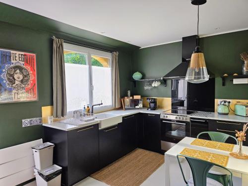 a kitchen with black cabinets and green walls at Maison Finchette pour 2 - 5 min Saint-Émilion - Terrasse privée - Parking - Arrivée autonome in Sainte-Terre
