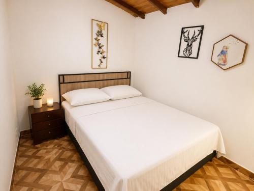 a bedroom with a white bed and a wooden floor at Aparta Suites Torre de Prado 502 Apartamento para 5 Personas in Medellín