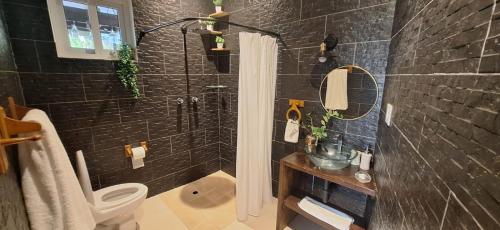 a black bathroom with a shower and a toilet at Stone Hill farm & cabins in Penonomé