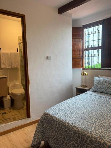 a bedroom with a bed and a bathroom with a toilet at Tángara Home in Cali