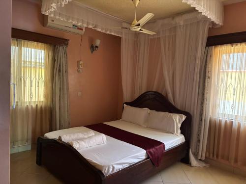 a bedroom with a bed with white sheets and a fan at Barizi Cottage in Tulu