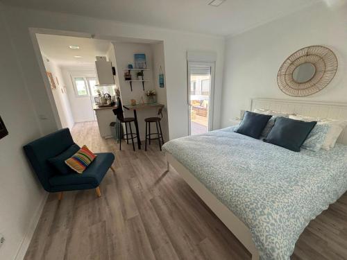 a bedroom with a bed and a chair and a kitchen at Blessed House in Portimão