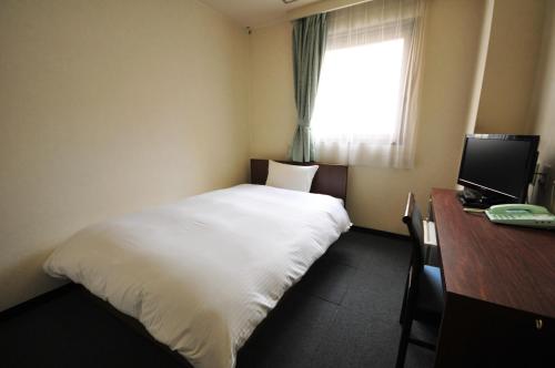 1 dormitorio con cama, escritorio y ventana en Hotel Green City, en Sendai