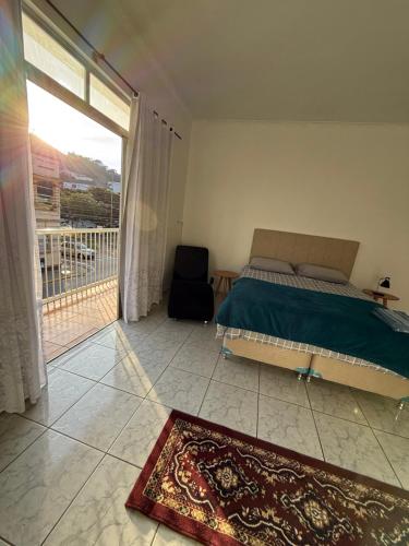 a bedroom with a bed and a window with a balcony at Kitnets Kretzer Hinckel 3 - CENTRO in Alfredo Wagner