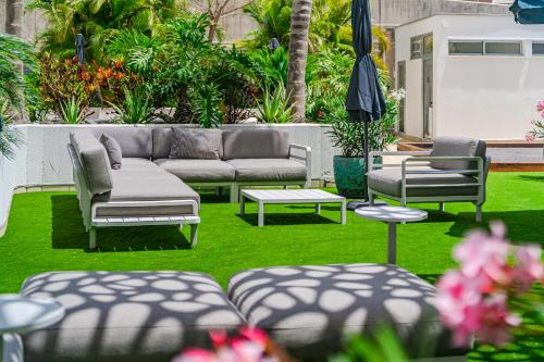 a patio with a couch and chairs on grass at Blue Gold Escape - Ocean view, airco, heated pool in Adeje